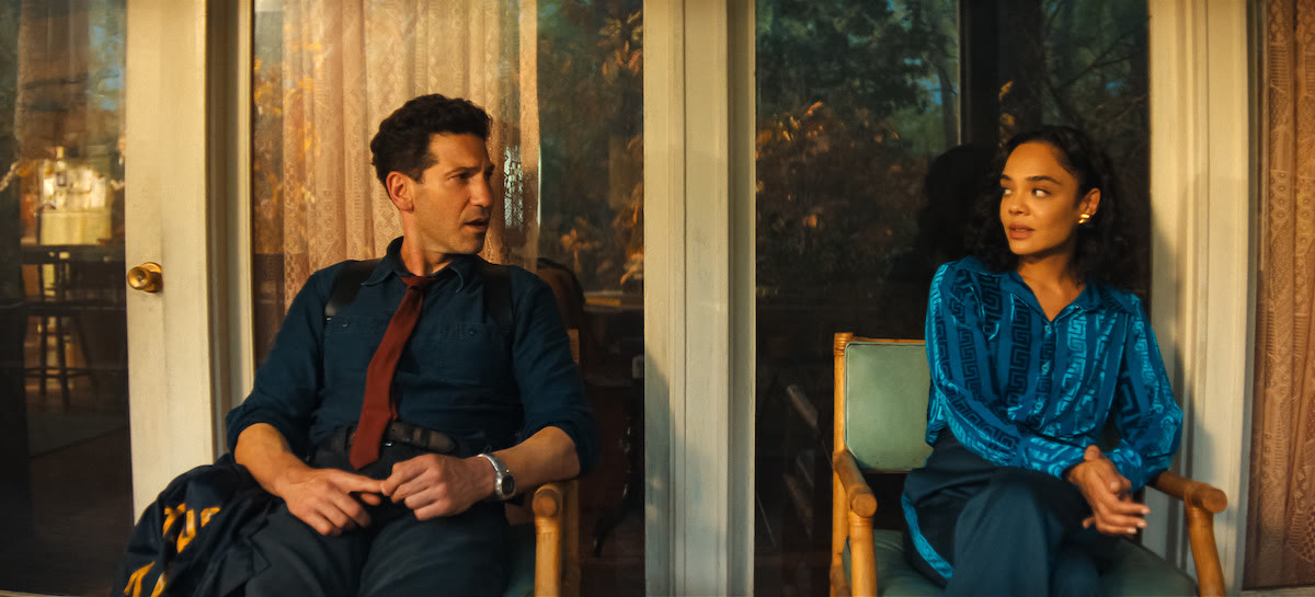 A man and woman seated opposite one another beside glass doors, His & Hers