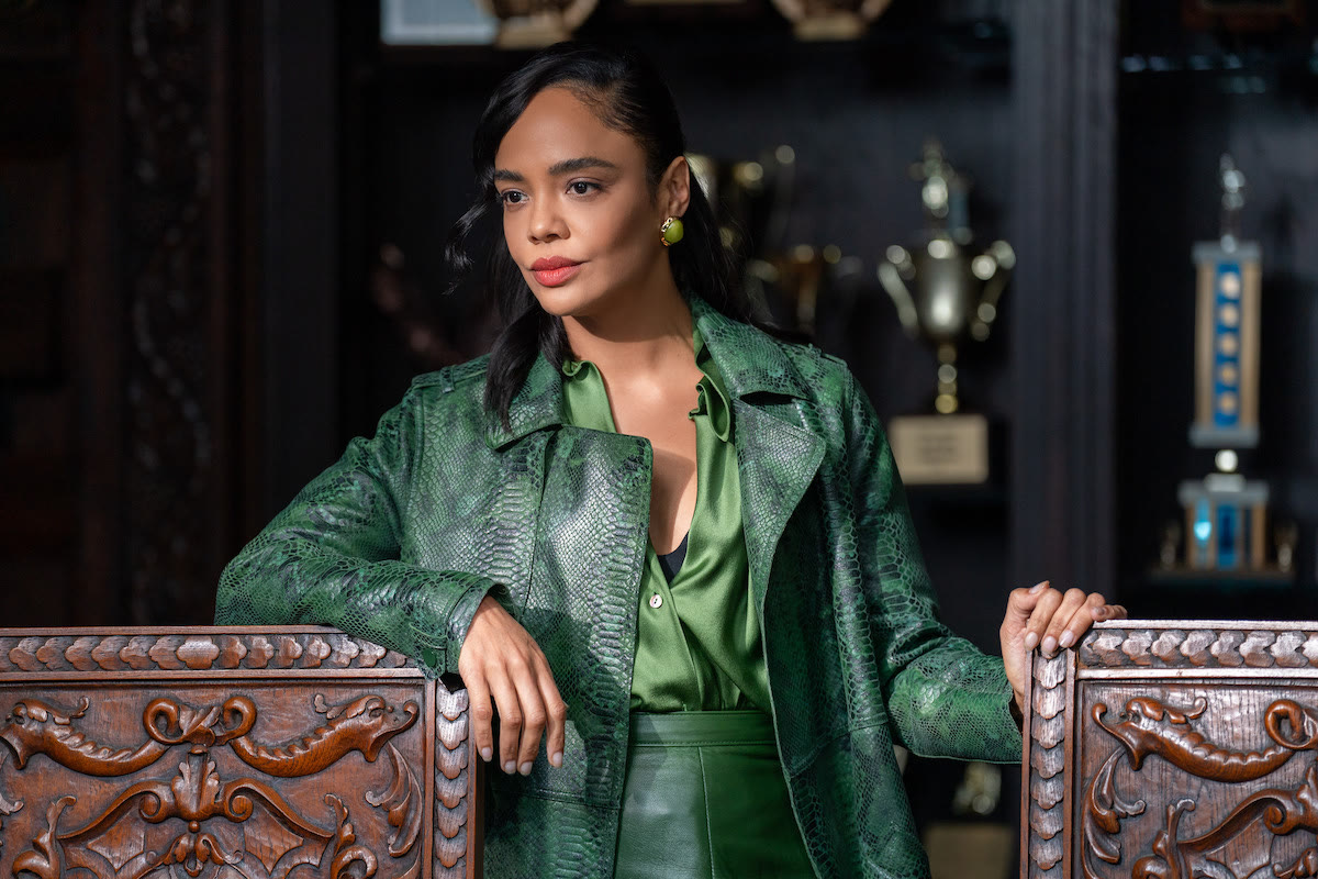 A woman in a green leather coat standing among display cases, His & Hers
