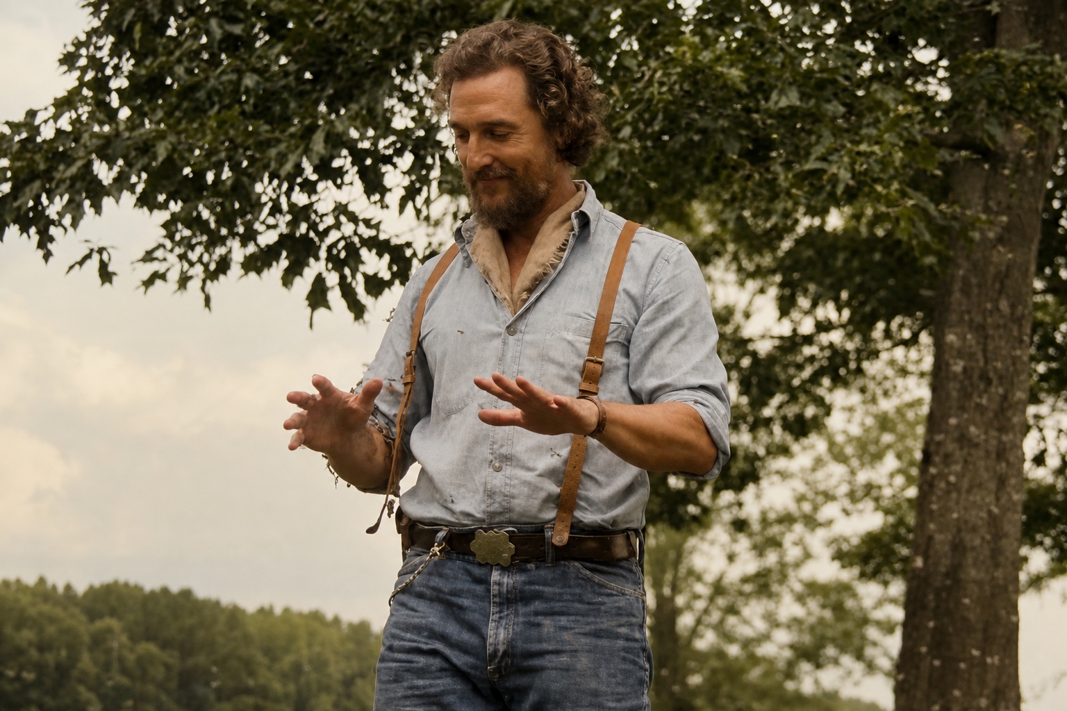 Matthew McConaughey and Angelina LookingGlass walking through an Oklahoma field in worn denim and layered workwear